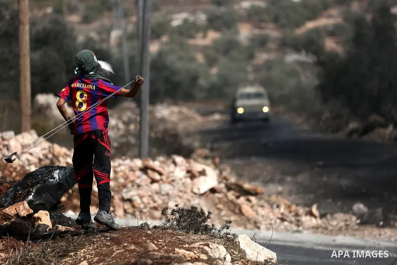 A Palestinian protester hurls stones towards Israeli troops during clashes near the Jewish settlement of Qadomem, in the West Bank village of Kofr Qadom near Nablus September 29, 2017. Photo by Ayman Ameen
