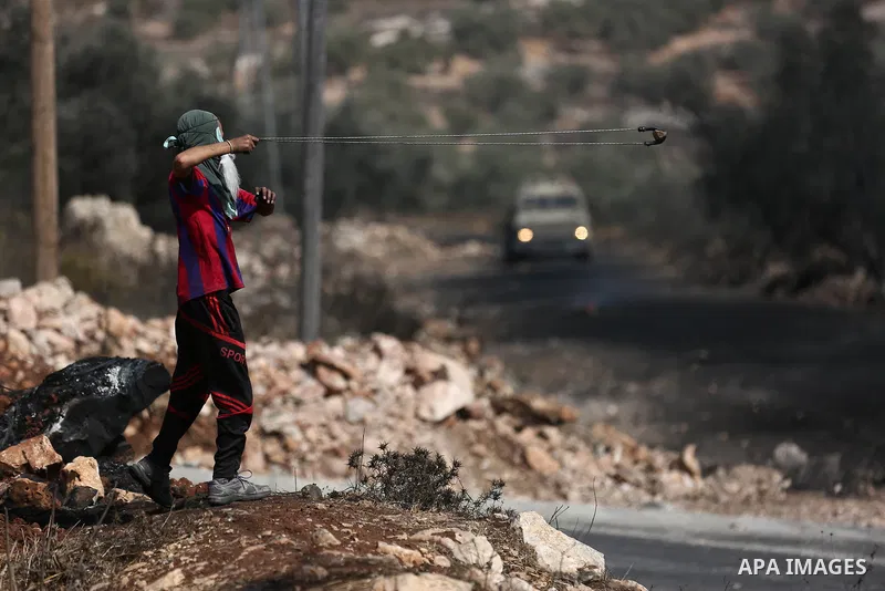 A Palestinian protester hurls stones towards Israeli troops during clashes near the Jewish settlement of Qadomem, in the West Bank village of Kofr Qadom near Nablus September 29, 2017. Photo by Ayman Ameen