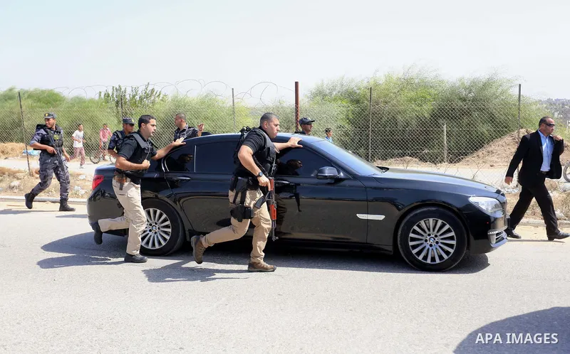 Palestinian security officers surround the vehicle carrying Prime Minister Rami Hamdallah upon his arrival with his government at Erez crossing in the northern Gaza Strip, on October 2, 2017. Hamdallah is on on his first...