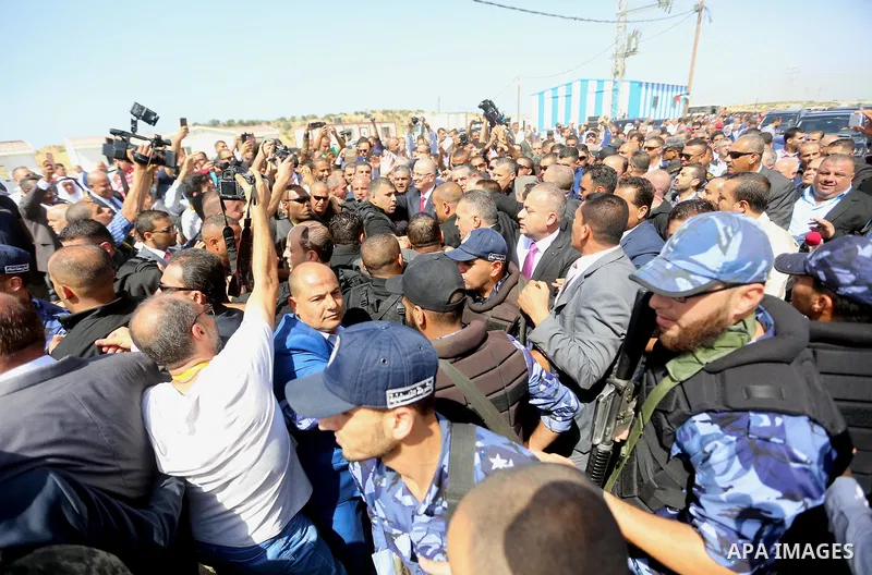 Palestinian Prime Minister Rami Hamdallah is surrounded by security as he waves following his arrival at the Erez border crossing in the northern Gaza Strip on October 2, 2017. Hamdallah is on on his first visit to the G...
