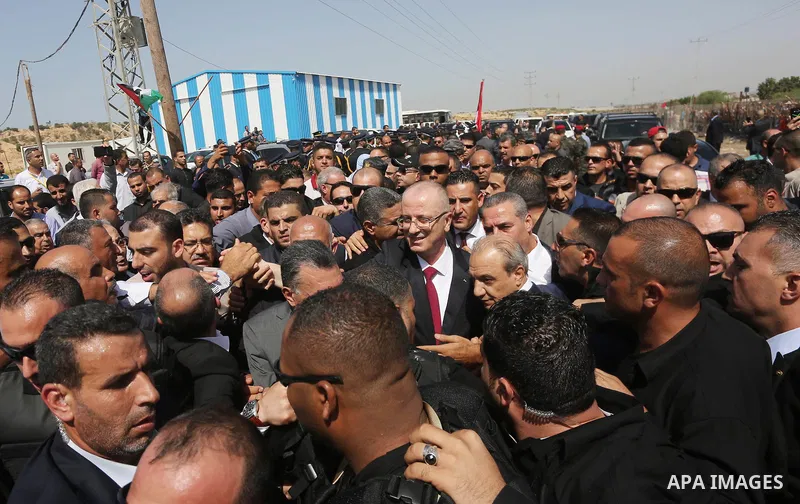 Palestinian Prime Minister Rami Hamdallah is surrounded by security as he waves following his arrival at the Erez border crossing in the northern Gaza Strip on October 2, 2017. Hamdallah is on on his first visit to the G...