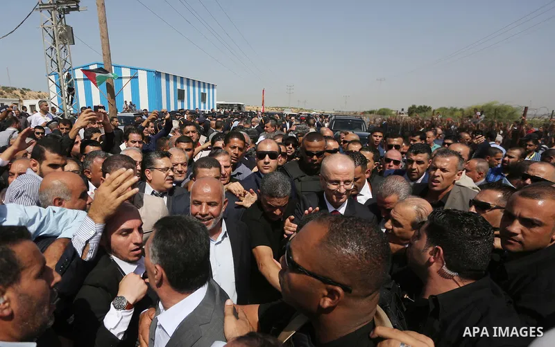 Palestinian Prime Minister Rami Hamdallah is surrounded by security as he waves following his arrival at the Erez border crossing in the northern Gaza Strip on October 2, 2017. Hamdallah is on on his first visit to the G...