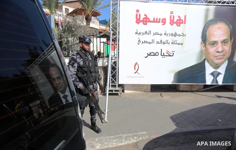 A member of Palestinian security forces stands guards next to a billboard bearing the portrait of Egyptian President Abdel Fattah al-Sisi near the Palestinian government headquarters in Gaza City on October 3, 2017. Phot...