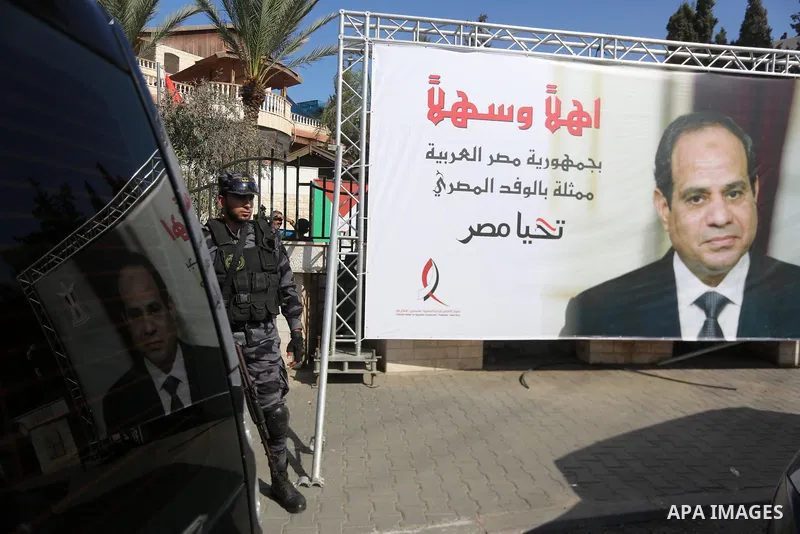 A member of Palestinian security forces stands guards next to a billboard bearing the portrait of Egyptian President Abdel Fattah al-Sisi near the Palestinian government headquarters in Gaza City on October 3, 2017. Phot...