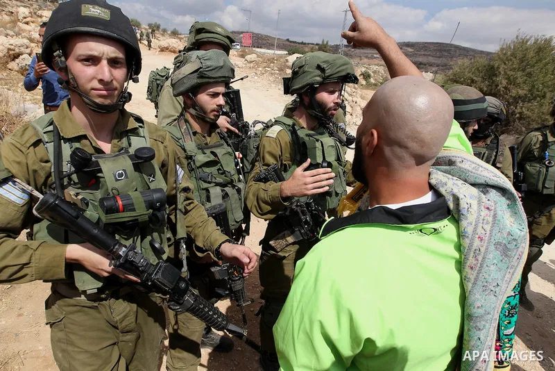 A Palestinian protester argues with Israeli security forces during a protest demanding the reopening of the main road to the Qalqas village that was closed by Israel almost 17 years ago in the West Bank city of Hebron Oc...