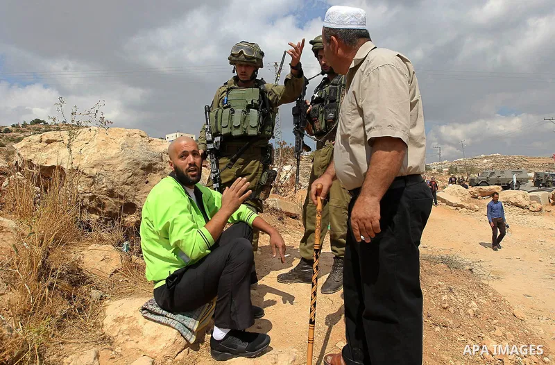 A Palestinian protester argues with Israeli security forces during a protest demanding the reopening of the main road to the Qalqas village that was closed by Israel almost 17 years ago in the West Bank city of Hebron Oc...