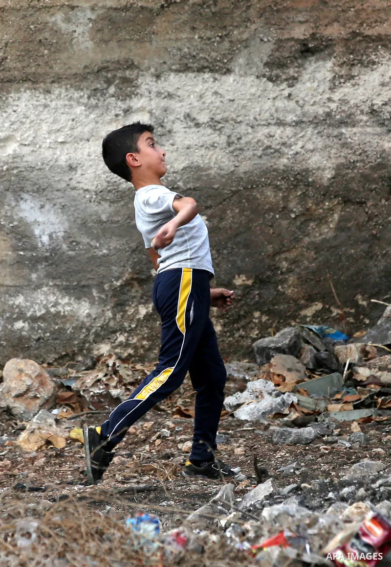 A Palestinian protester throws stones towards Israeli security forces during clashes following a demonstration against the expropriation of Palestinian land by Israel in the village of Kfar Qaddum, near Nablus in the occ...