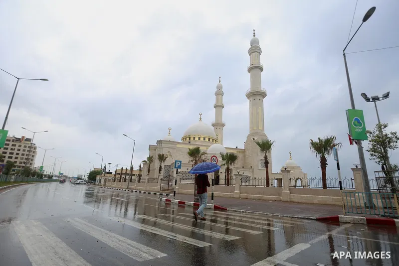 A Palestinian man walks in a street flooded by rain water, in Gaza city on October 9, 2017. Photo by Atia Darwish