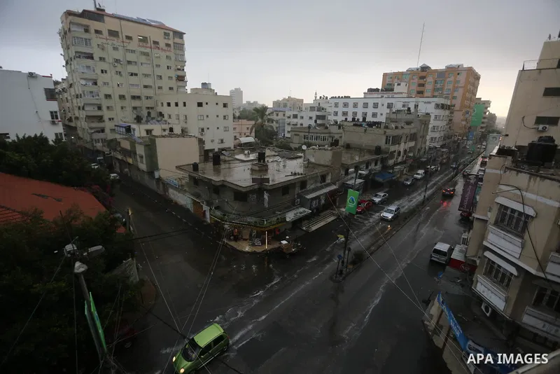 Palestinians walk in a street flooded by rain water, in Gaza city on October 9, 2017. Photo by Atia Darwish