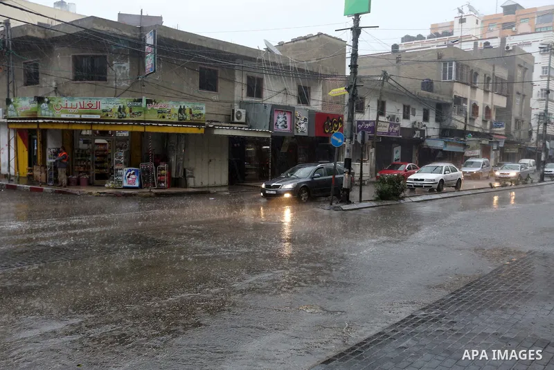 Palestinians walk in a street flooded by rain water, in Gaza city on October 9, 2017. Photo by Atia Darwish