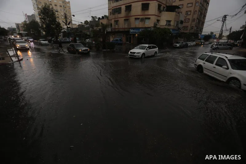 Palestinians walk in a street flooded by rain water, in Gaza city on October 9, 2017. Photo by Atia Darwish