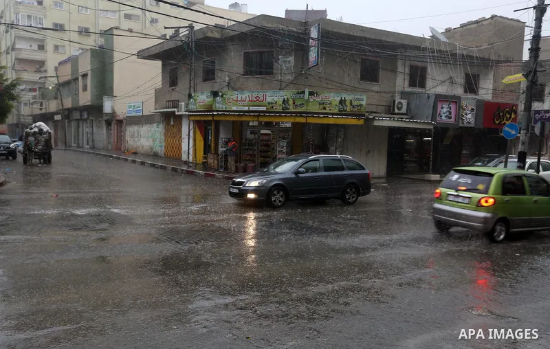 Palestinians walk in a street flooded by rain water, in Gaza city on October 9, 2017. Photo by Atia Darwish