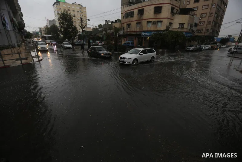 Palestinians walk in a street flooded by rain water, in Gaza city on October 9, 2017. Photo by Atia Darwish