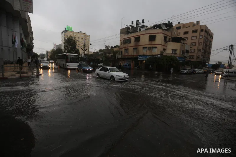 Palestinians walk in a street flooded by rain water, in Gaza city on October 9, 2017. Photo by Atia Darwish