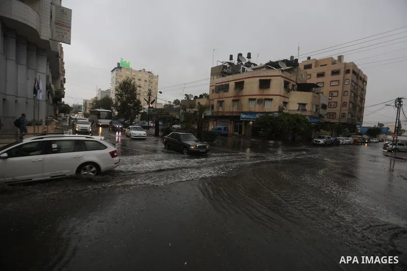 Palestinians walk in a street flooded by rain water, in Gaza city on October 9, 2017. Photo by Atia Darwish