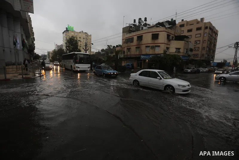 Palestinians walk in a street flooded by rain water, in Gaza city on October 9, 2017. Photo by Atia Darwish