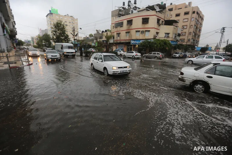 Palestinians walk in a street flooded by rain water, in Gaza city on October 9, 2017. Photo by Atia Darwish