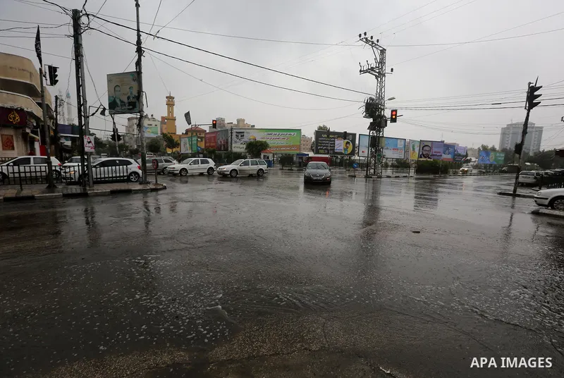 Palestinians walk in a street flooded by rain water, in Gaza city on October 9, 2017. Photo by Atia Darwish