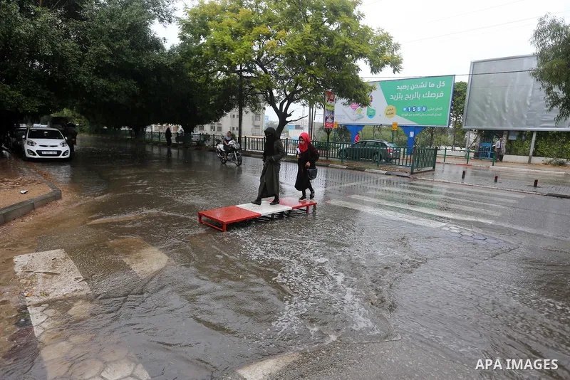 Palestinian students walk in a street flooded by rain water, in Gaza city on October 9, 2017. Photo by Atia Darwish
