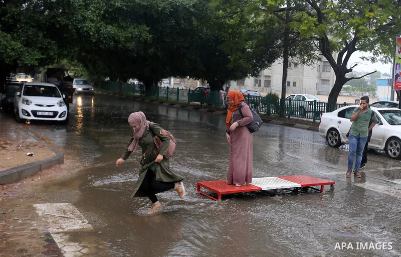 Palestinian students walk in a street flooded by rain water, in Gaza city on October 9, 2017. Photo by Atia Darwish