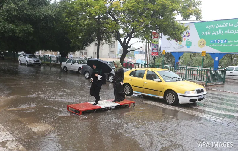 Palestinian students walk in a street flooded by rain water, in Gaza city on October 9, 2017. Photo by Atia Darwish