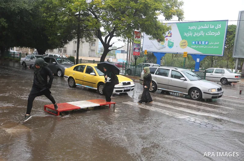 Palestinian students walk in a street flooded by rain water, in Gaza city on October 9, 2017. Photo by Atia Darwish