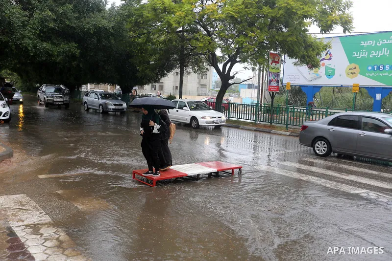 Palestinian students walk in a street flooded by rain water, in Gaza city on October 9, 2017. Photo by Atia Darwish