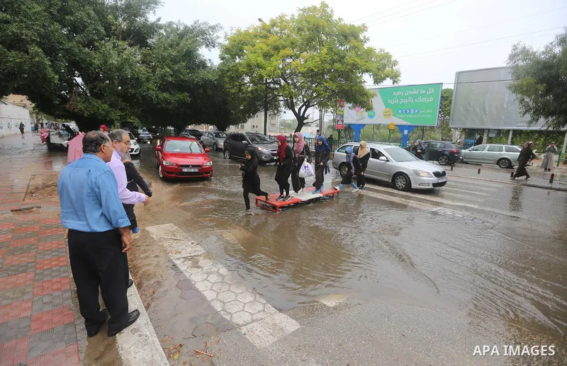 Palestinian students walk in a street flooded by rain water, in Gaza city on October 9, 2017. Photo by Atia Darwish