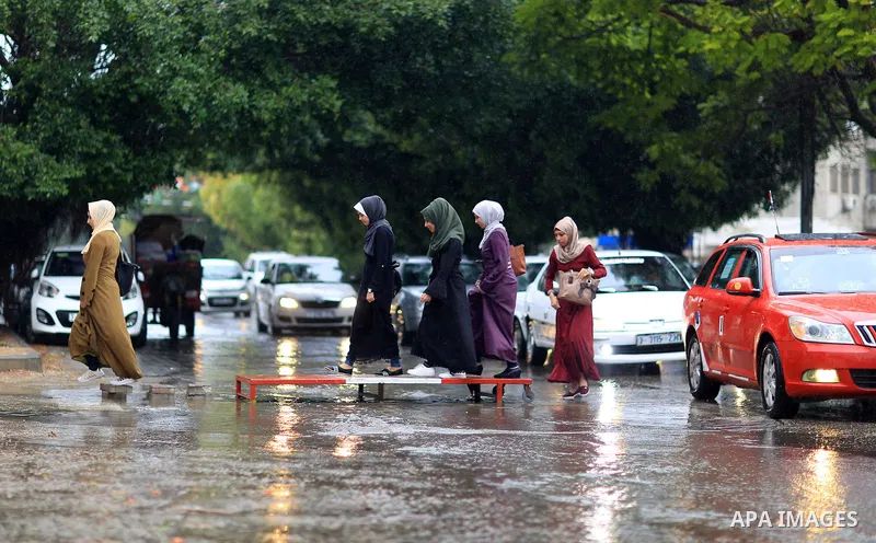 Palestinian students walk in a street flooded by rain water, in Gaza city on October 9, 2017. Photo by Atia Darwish