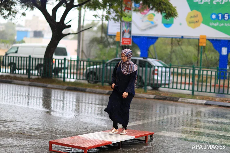 A Palestinian student walks in a street flooded by rain water, in Gaza city on October 9, 2017. Photo by Atia Darwish