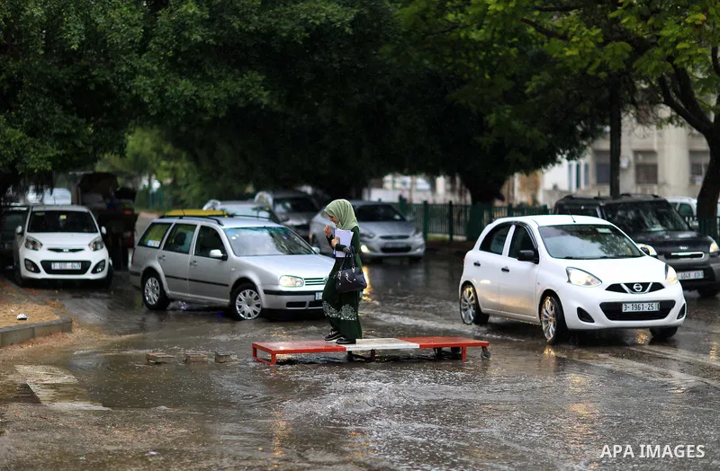 Palestinian students walk in a street flooded by rain water, in Gaza city on October 9, 2017. Photo by Atia Darwish