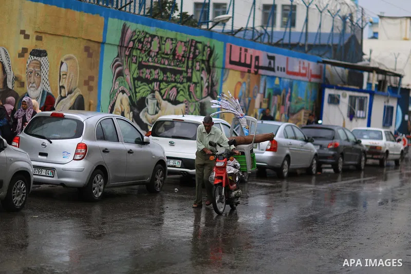 Palestinians walk in a street flooded by rain water, in Gaza city on October 9, 2017. Photo by Atia Darwish