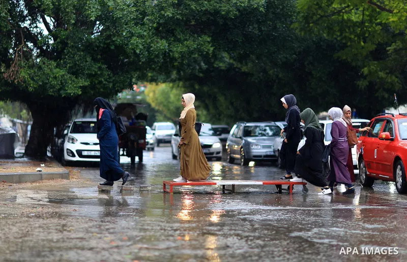 Palestinian students walk in a street flooded by rain water, in Gaza city on October 9, 2017. Photo by Atia Darwish
