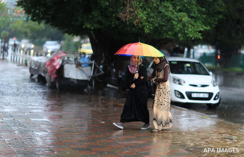 Palestinian students walk in a street flooded by rain water, in Gaza city on October 9, 2017. Photo by Atia Darwish