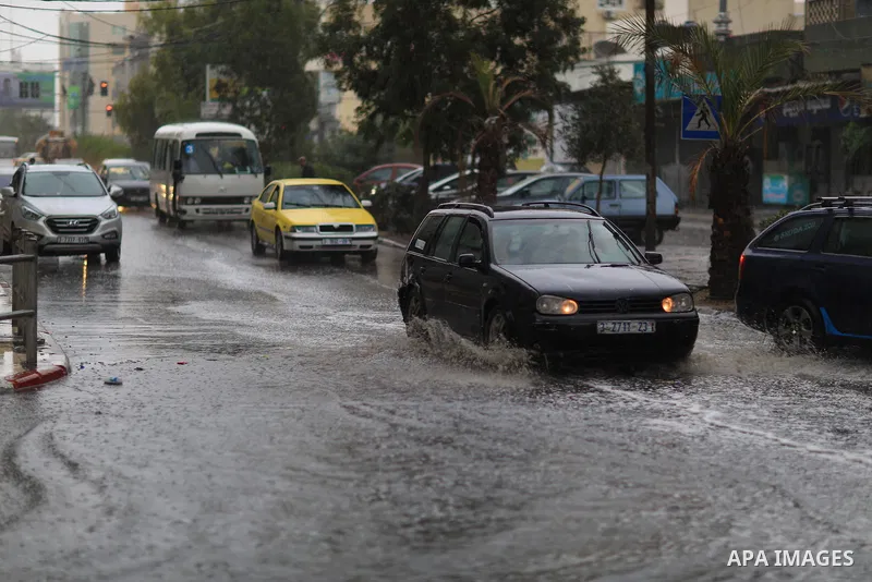 Palestinians walk in a street flooded by rain water, in Gaza city on October 9, 2017. Photo by Atia Darwish