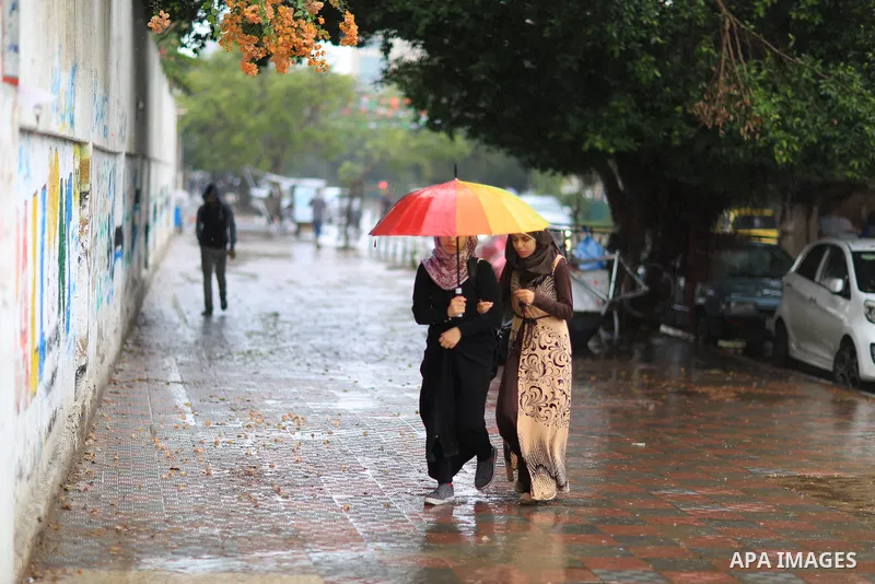 Palestinian students walk in a street flooded by rain water, in Gaza city on October 9, 2017. Photo by Atia Darwish