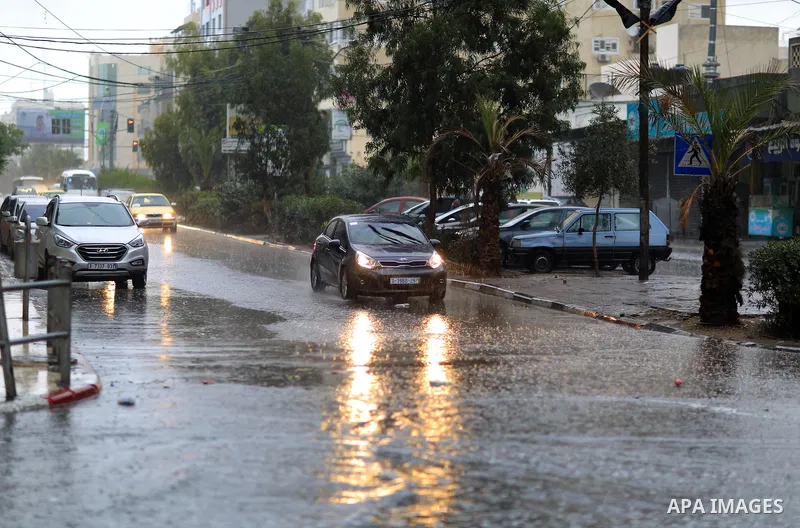 Palestinians walk in a street flooded by rain water, in Gaza city on October 9, 2017. Photo by Atia Darwish