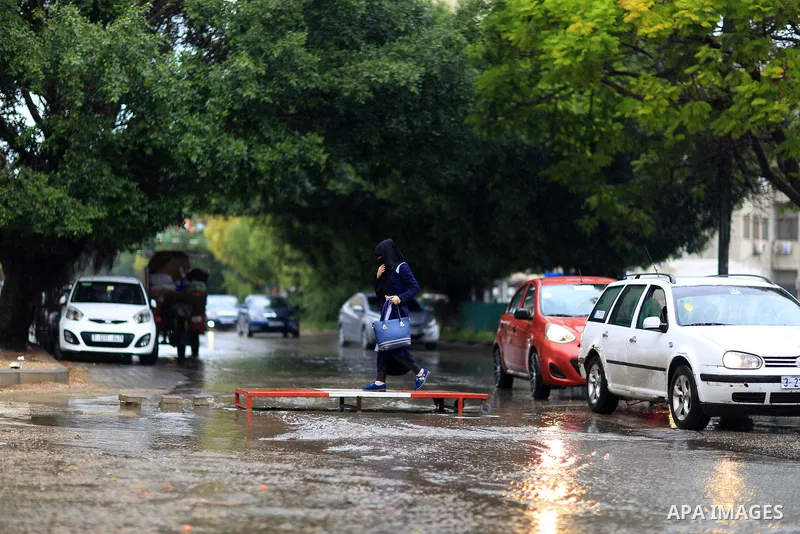 Palestinian students walk in a street flooded by rain water, in Gaza city on October 9, 2017. Photo by Atia Darwish