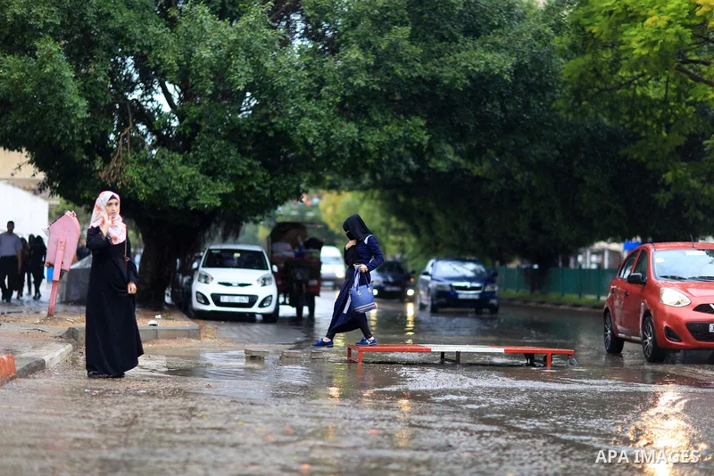 Palestinian students walk in a street flooded by rain water, in Gaza city on October 9, 2017. Photo by Atia Darwish