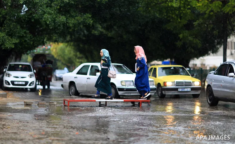 Palestinian students walk in a street flooded by rain water, in Gaza city on October 9, 2017. Photo by Atia Darwish