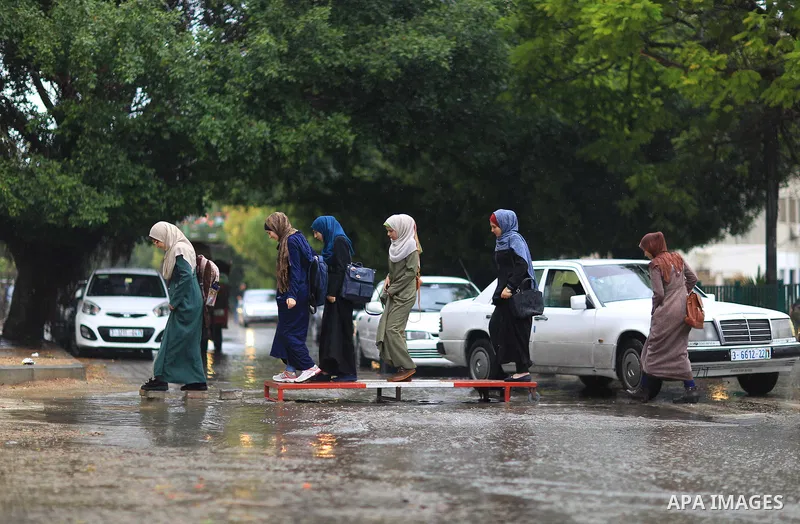 Palestinian students walk in a street flooded by rain water, in Gaza city on October 9, 2017. Photo by Atia Darwish