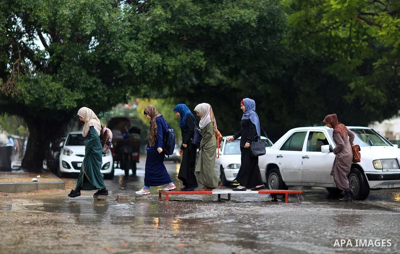 Palestinian students walk in a street flooded by rain water, in Gaza city on October 9, 2017. Photo by Atia Darwish