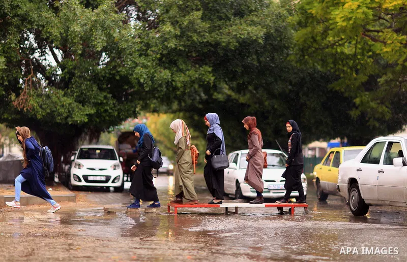 Palestinian students walk in a street flooded by rain water, in Gaza city on October 9, 2017. Photo by Atia Darwish
