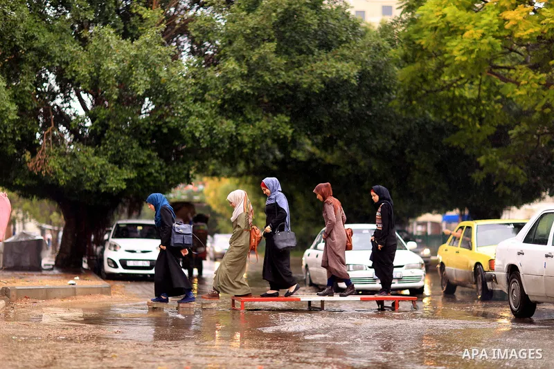 Palestinian students walk in a street flooded by rain water, in Gaza city on October 9, 2017. Photo by Atia Darwish