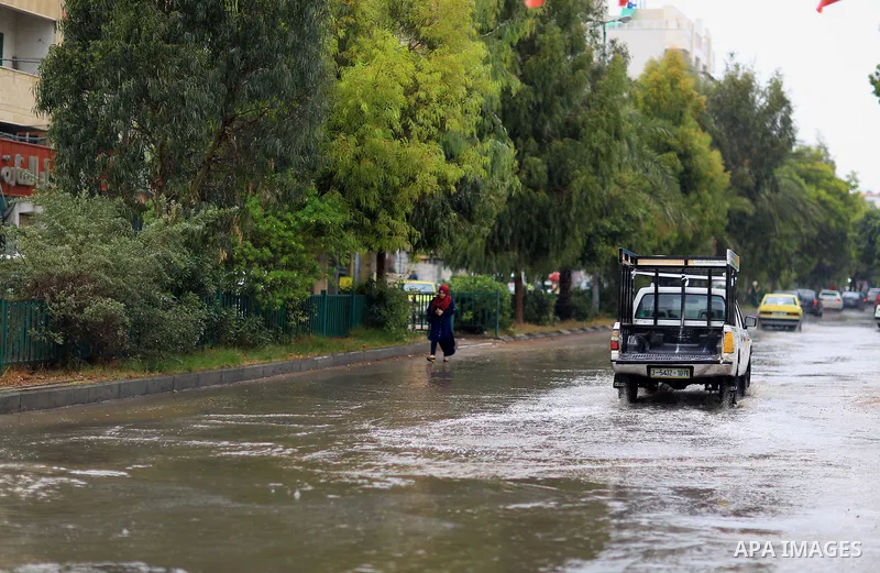 Palestinians walk in a street flooded by rain water, in Gaza city on October 9, 2017. Photo by Atia Darwish