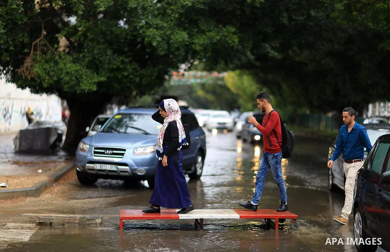 Palestinian students walk in a street flooded by rain water, in Gaza city on October 9, 2017. Photo by Atia Darwish