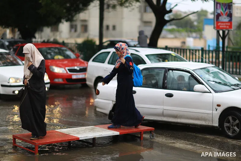 Palestinian students walk in a street flooded by rain water, in Gaza city on October 9, 2017. Photo by Atia Darwish