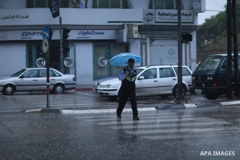 A Palestinian traffic policeman works in a street during heavy rains, in Gaza city on October 9, 2017. Photo by Atia Darwish