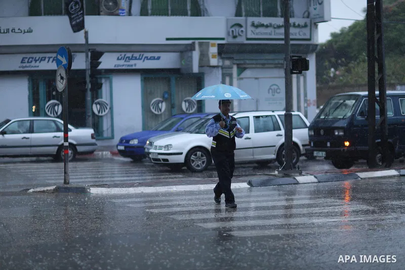 A Palestinian traffic policeman works in a street during heavy rains, in Gaza city on October 9, 2017. Photo by Atia Darwish