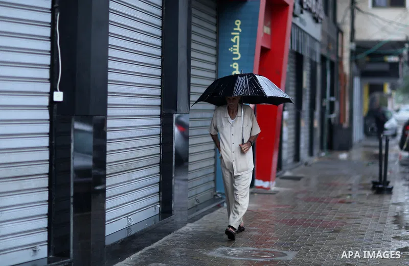 A Palestinian man walks in a street flooded by rain water, in Gaza city on October 9, 2017. Photo by Atia Darwish